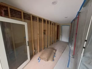 Demolished hallway with exposed studs and dust mitigation installed for construction.