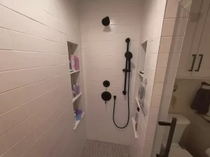 Shower featuring white subway tile walls, black fixtures, and hexagonal floor tiling for a modern aesthetic.
