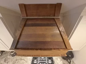 Close-up of a rustic reclaimed wood range hood in a modern kitchen, blending farmhouse charm with contemporary design elements.