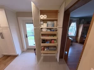 Pull-out storage with organized paper products and kitchen essentials, showcasing Stately Kitchen and Bath’s storage solutions.