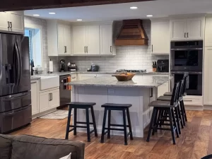 Elegant kitchen with wooden flooring, marble island, and modern stainless steel appliances.