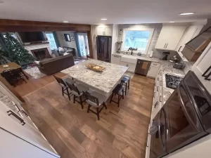 Open-concept kitchen and living space renovation by Stately Kitchen and Bath, showcasing a large island and hardwood floors.
