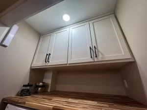 Close-up of a laundry room with sleek white cabinets and a butcher block countertop.