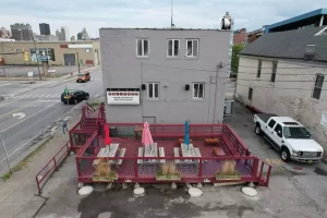 Outdoor patio at Ballyhoo Buffalo with picnic tables and umbrellas, ready for Stately Pole Barns’ custom covered deck transformation.