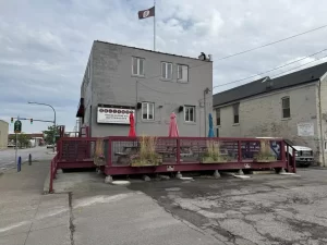 Side angle of Ballyhoo Buffalo’s patio before covered deck installation by Stately Pole Barns, featuring rustic picnic seating.