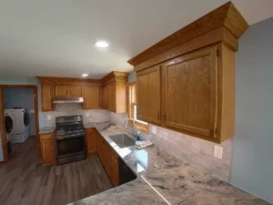 Custom Stately kitchen renovation with refinished cabinets, modern range hood, and expertly-laid tile backsplash.