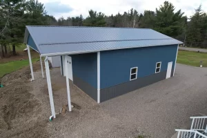 Rear overhang view of custom post-frame pole barn with covered porch and insulated overhead door.