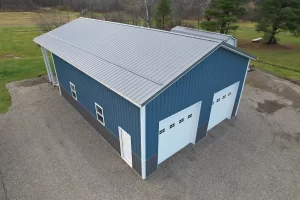 Angled aerial of steel-sided pole barn highlighting white trim, charcoal wainscot, and precision roofline.