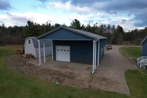 Rear and side view of pole barn showing ocean blue steel panels and vented eaves in a residential setting.