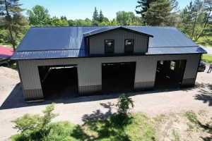 Front elevation of Stately-built pole barn with three framed overhead door openings and architectural gable.