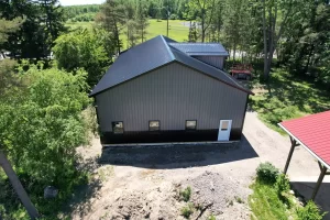 Side view of Stately pole barn showing matte black steel panels, windows, and white entry door.