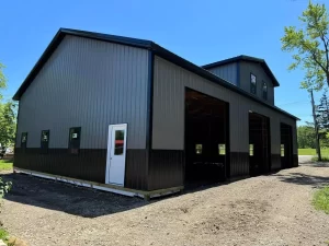 Matte black post-frame barn with reverse gable and overhead door bays, built by Stately in Elma, NY.