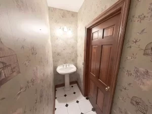 Vintage Amherst NY powder room with floral birdcage wallpaper, pedestal sink, and black and white tile flooring.