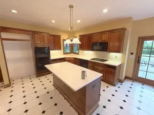Amherst NY kitchen pre-remodel with gas cooktop, double oven, center island, wood cabinetry, and patio access.