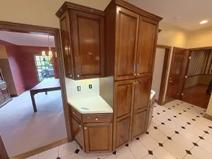 Amherst NY kitchen corner with tall wood pantry cabinets, undercabinet lighting prep zone, and view into dining room.