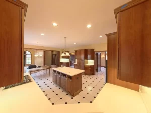Amherst NY kitchen pre-remodel view with center island, wood cabinetry, recessed lighting, and open layout to dining area.