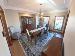 Amherst NY dining room remodel with neutral paint, updated chandelier, hardwood floors, and classic crown molding detail.