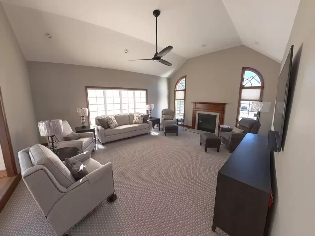 Amherst NY living room remodel with vaulted ceiling, modern ceiling fan, neutral walls, new carpet, and cozy furniture layout.