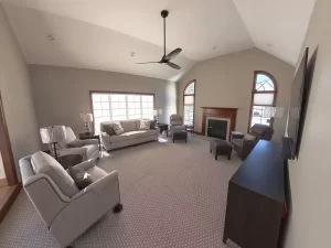 Amherst NY living room remodel with vaulted ceiling, modern ceiling fan, neutral walls, new carpet, and cozy furniture layout.