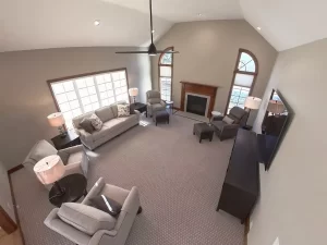 Amherst NY living room remodel with modern furnishings, vaulted ceiling, large windows, and centered fireplace wall.