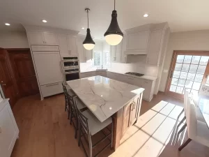 Amherst NY kitchen remodel with marble-look island, white shaker cabinets, double oven, and pendant lighting.