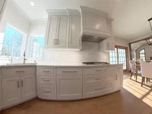 Amherst NY kitchen remodel with shaker cabinets, undercabinet lighting, brass faucet, gas cooktop, and subway tile backsplash.
