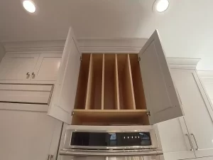 Amherst NY kitchen remodel with upper cabinet featuring vertical dividers for cutting boards and trays above built-in oven.