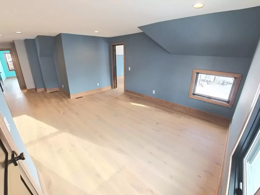 Custom bonus room with light hardwood flooring, recessed lighting, and trimmed window details in Buffalo-area home renovation.