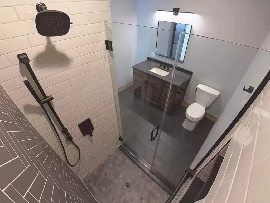 Full view of bathroom with walk-in glass shower, matte black fixtures, and dark wood vanity in Buffalo custom renovation.