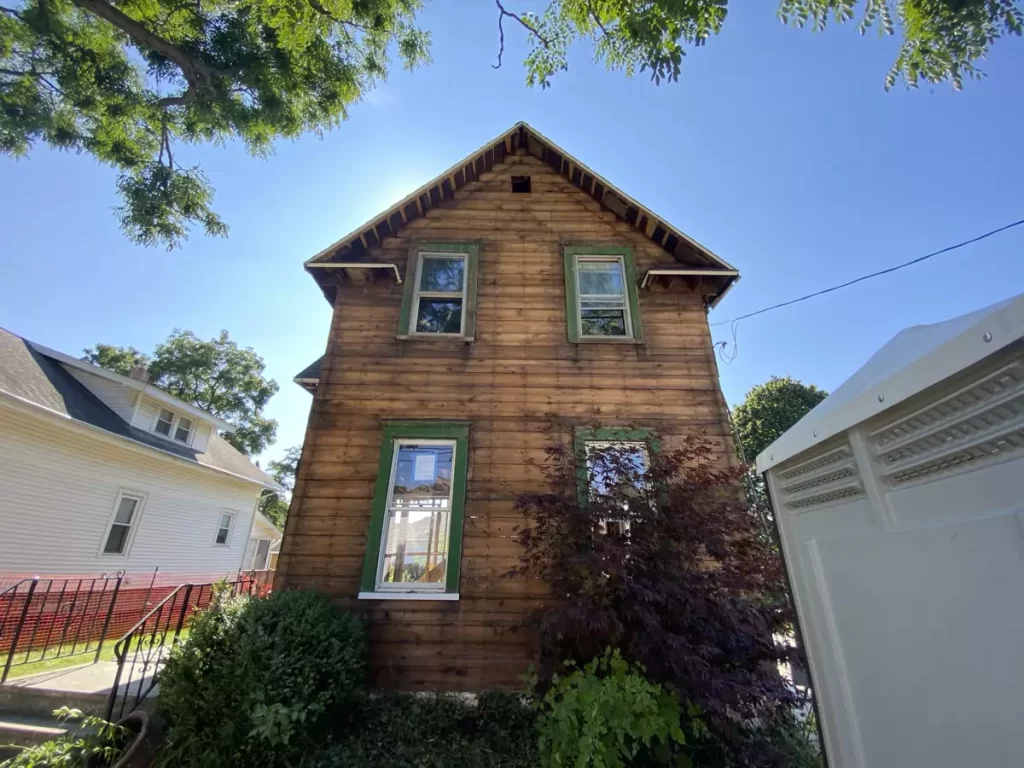 Side view of home with siding removed, exposing original wood sheathing and framing during Buffalo remodel.