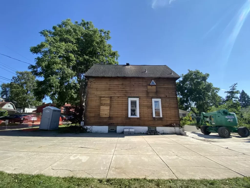 Back view of stripped home with exposed wood framing and construction equipment during Buffalo renovation.
