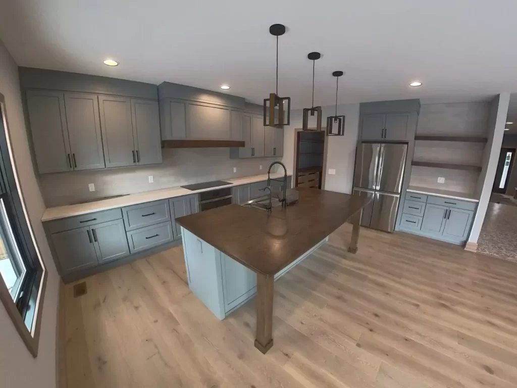 Custom kitchen with gray shaker cabinetry, wood island, pendant lights, and open shelving in Buffalo home renovation.