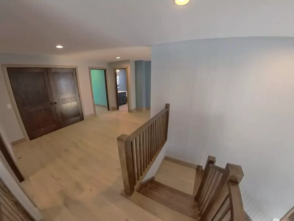 Upstairs landing with hardwood floors, custom stair railing, dark wood doors, and recessed lighting in Buffalo home addition.