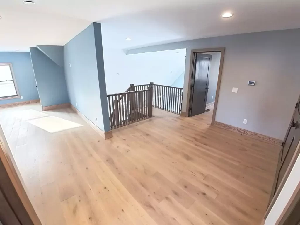 Open upstairs landing with wood flooring, custom railing, and modern trim work in Buffalo-area home addition.