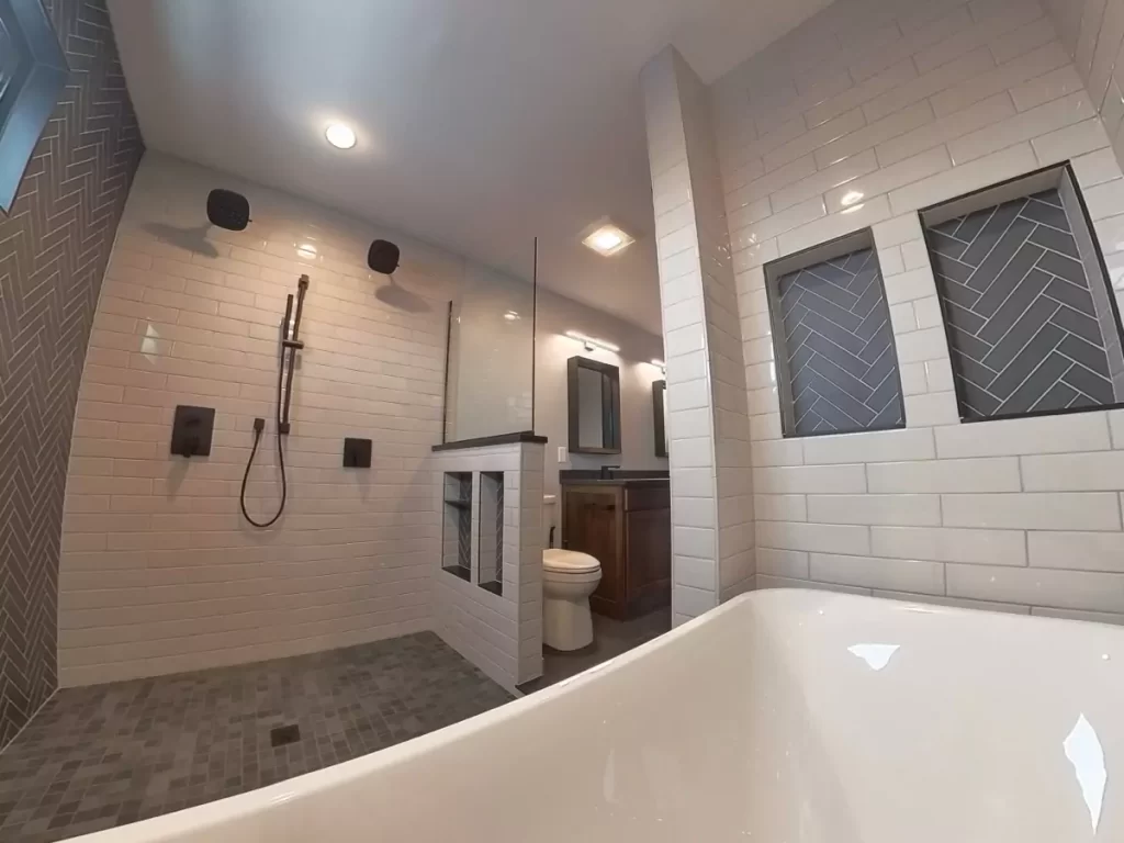 Dual showerheads, built-in niches with herringbone tile, and freestanding tub in Buffalo luxury wet room design.