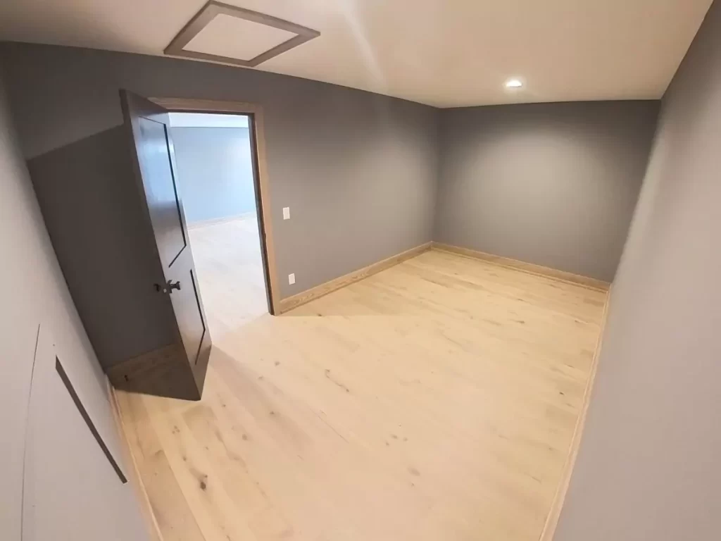 Walk-in closet with light wood flooring, soft gray walls, recessed ceiling light, and an open doorway leading to the primary bedroom.