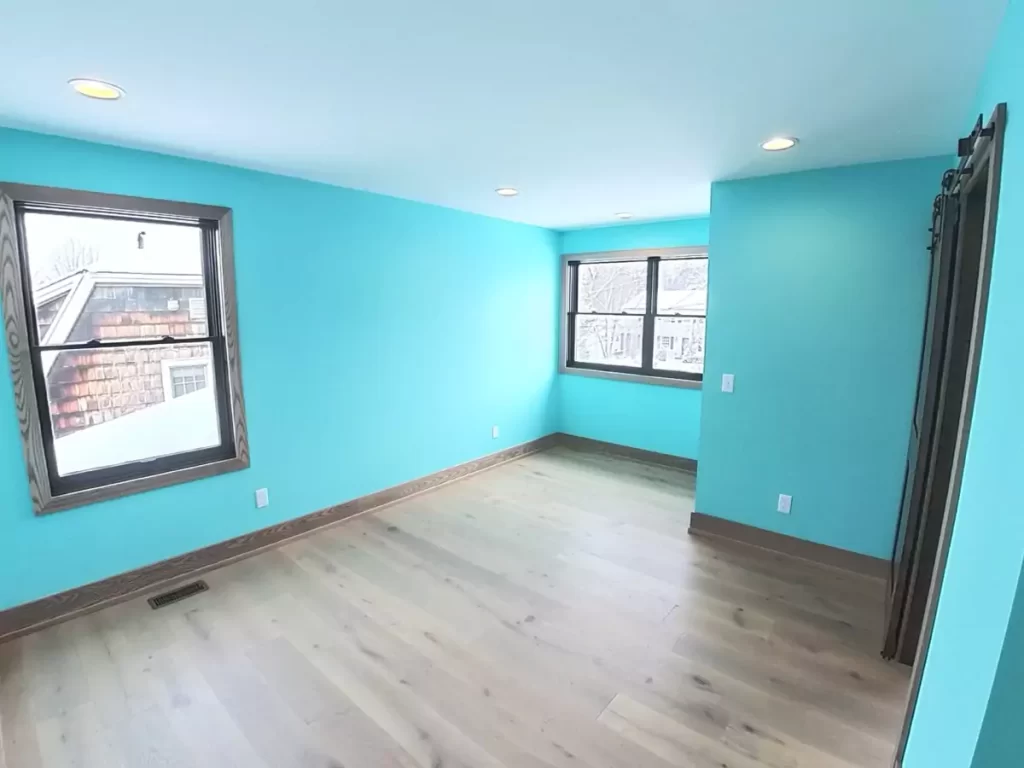 Bright secondary bedroom with turquoise walls and natural light in Buffalo-area home addition renovation.