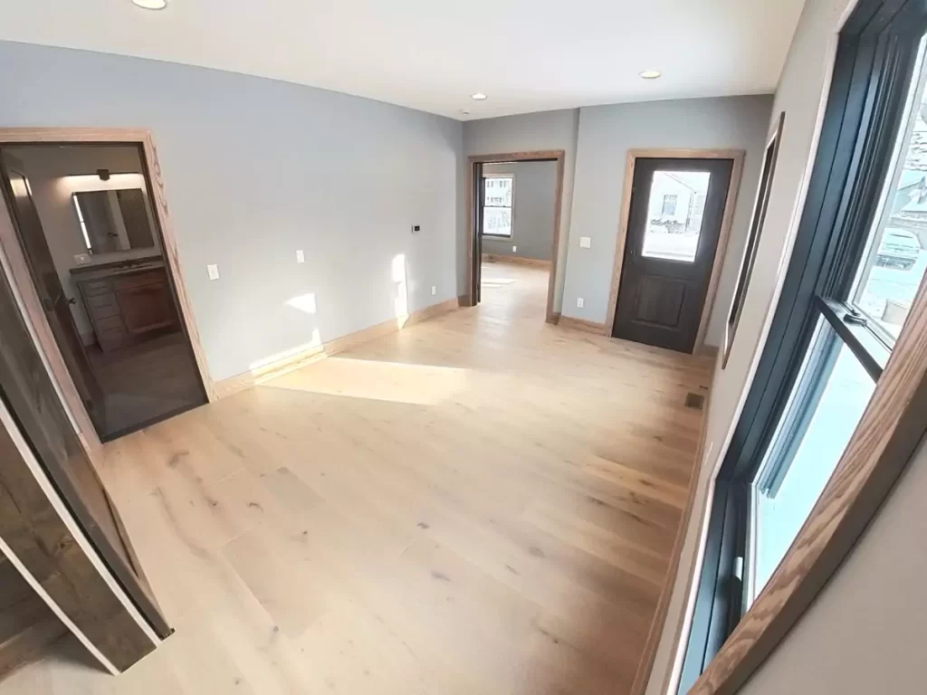 Bright side entryway in Buffalo home renovation, featuring access to the primary suite and original entry door with natural wood trim.