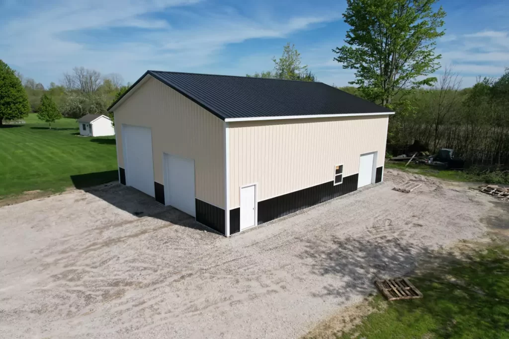 Side view of custom post-frame garage in Amherst NY with steel siding, overhead doors, and black wainscoting.