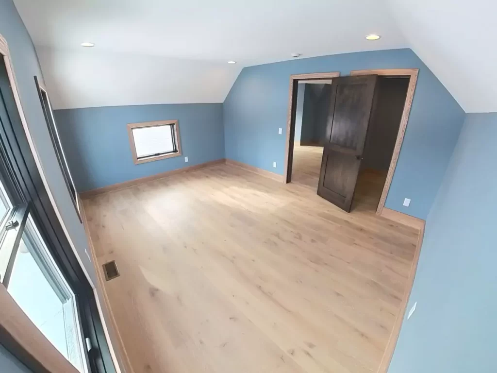 Third-floor bedroom in Buffalo renovation with blue walls, light oak flooring, and upgraded trim from the home addition project.