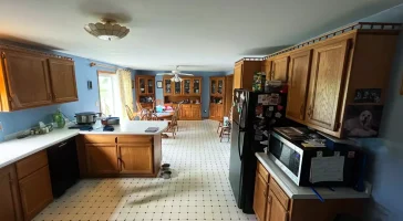 Wide view of Akron kitchen before Stately’s updates, featuring older cabinetry, old flooring, and dated fixtures.