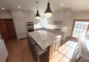 Amherst NY kitchen remodel with marble-look island, white shaker cabinets, double oven, and pendant lighting.
