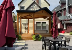 Wide shot of beer garden with soundstage at Buffalo Olde Brewing, showcasing comfortable seating and a wooden stage for live events.
