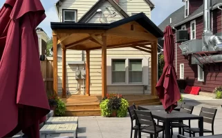 Wide shot of beer garden with soundstage at Buffalo Olde Brewing, showcasing comfortable seating and a wooden stage for live events.