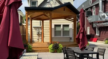 Wide shot of beer garden with soundstage at Buffalo Olde Brewing, showcasing comfortable seating and a wooden stage for live events.