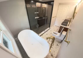 After photo of a bathroom remodel with a luxurious walk-in shower, black tile walls, and brass rain showerhead.