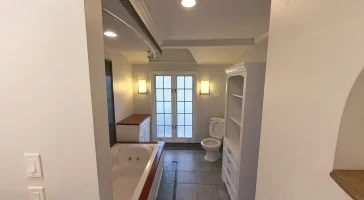 Before photo of a bathroom with a whirlpool tub, outdated cabinetry, and tile flooring.