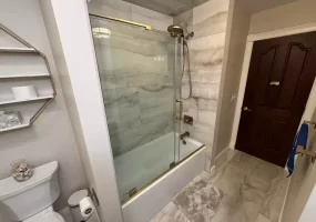 Glass-paned sliding shower door with gold accents.