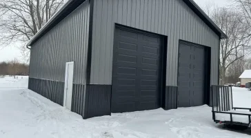 A Stately Pole Barn in East Amherst, NY, showcasing its sharp black and grey color scheme against a snowy backdrop.