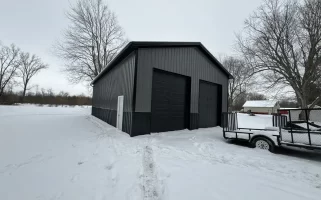 A Stately Pole Barn in East Amherst, NY, showcasing its sharp black and grey color scheme against a snowy backdrop.